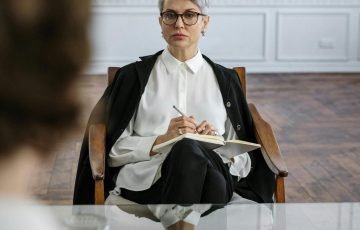 A professional therapist conducts a counseling session in a modern, minimalist office setting.